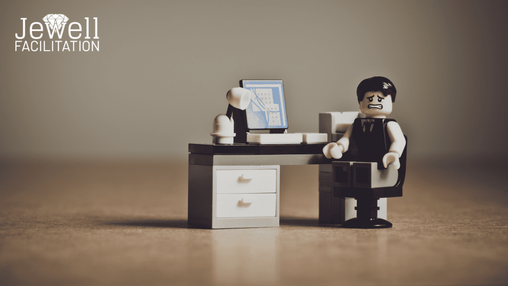 A professional workshop facilitator in lego form, sitting at his desk, looking stressed