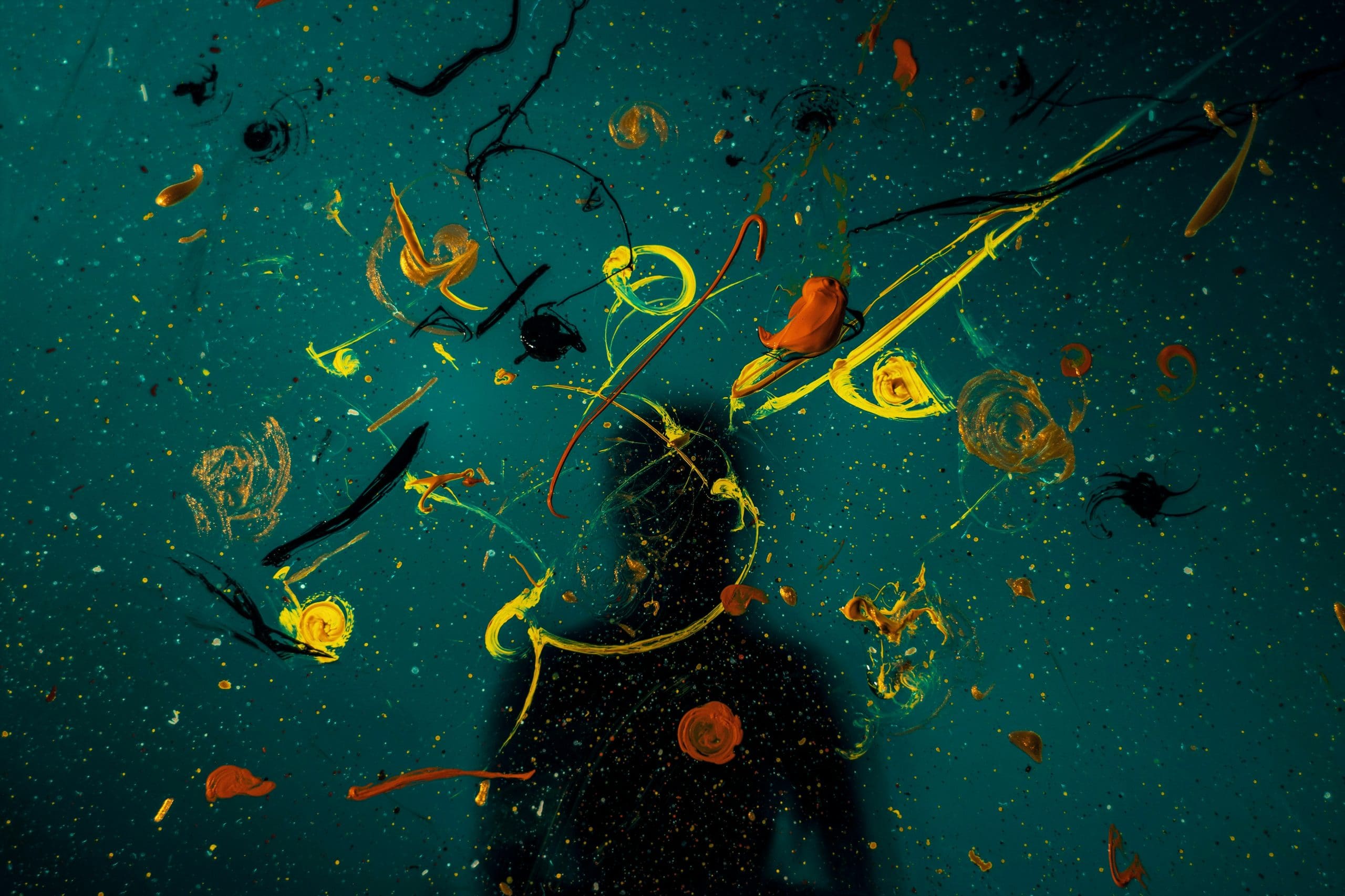 A photo of splattered paint on a green background with a human shaped shadow behind showing how innovative ideas for a team away day are made