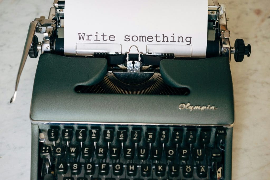 An old fashioned typewriter with the words 'write something' on the paper in it.